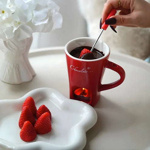 Taza roja con chocolate derretido y una fresa en el tenedor